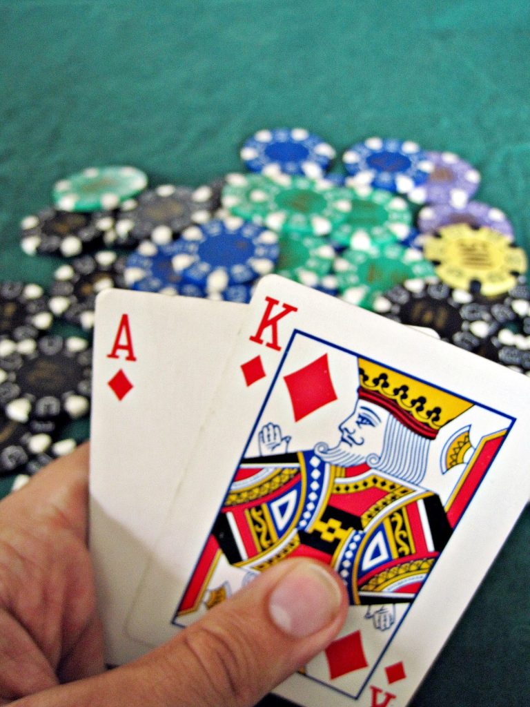 Gsc108 login Bonuses: Rewards and Features That Unlock After Signing In Hand holding ace and king cards over a pile of poker chips